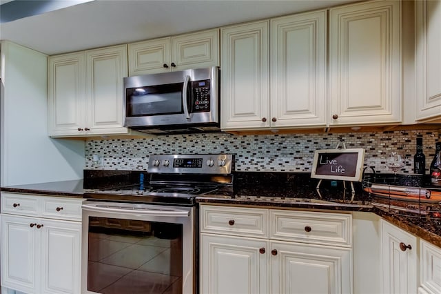 kitchen with white cabinets, appliances with stainless steel finishes, decorative backsplash, and dark stone counters