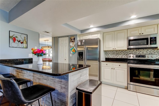 kitchen featuring visible vents, appliances with stainless steel finishes, decorative backsplash, and a breakfast bar area