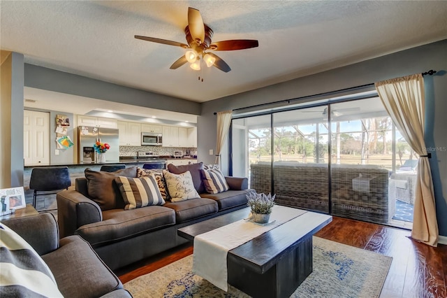 living room featuring ceiling fan, dark wood-type flooring, a textured ceiling, and plenty of natural light