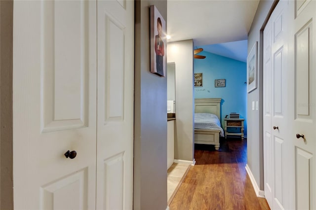 hallway with vaulted ceiling, wood finished floors, and baseboards