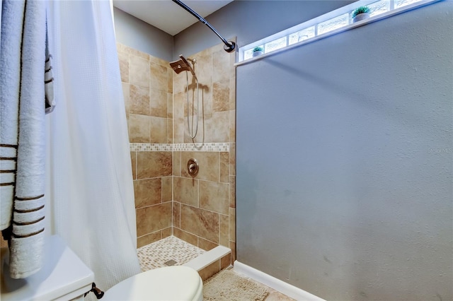 bathroom featuring a stall shower, baseboards, and toilet