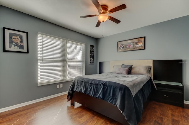 bedroom featuring dark wood-style flooring, a ceiling fan, and baseboards