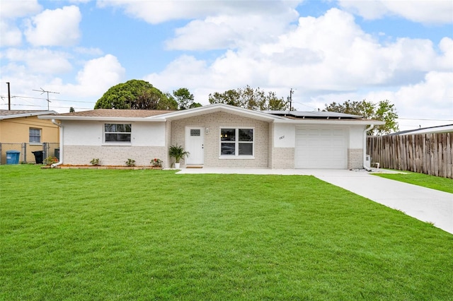 single story home with concrete driveway, a front lawn, an attached garage, and roof mounted solar panels