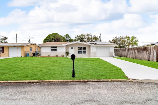 single story home with an attached garage, solar panels, fence, concrete driveway, and a front lawn