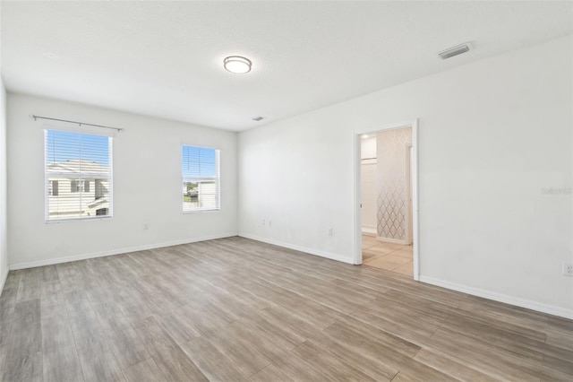 unfurnished room with wood finished floors, visible vents, and baseboards