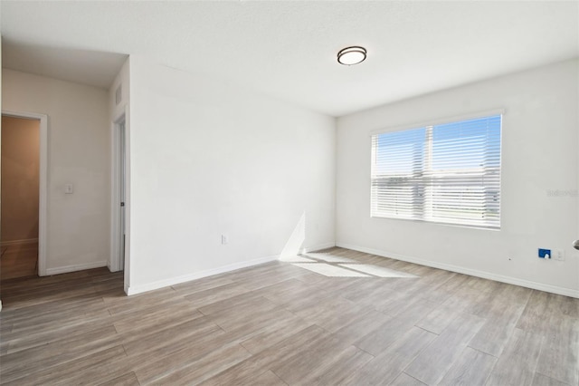 unfurnished room with baseboards, visible vents, and light wood finished floors