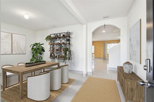 dining space with arched walkways, visible vents, baseboards, and light tile patterned floors