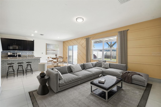 living area with light tile patterned floors, wooden walls, and visible vents