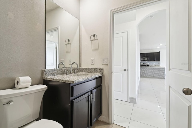 half bathroom with a textured wall, vanity, tile patterned flooring, and toilet