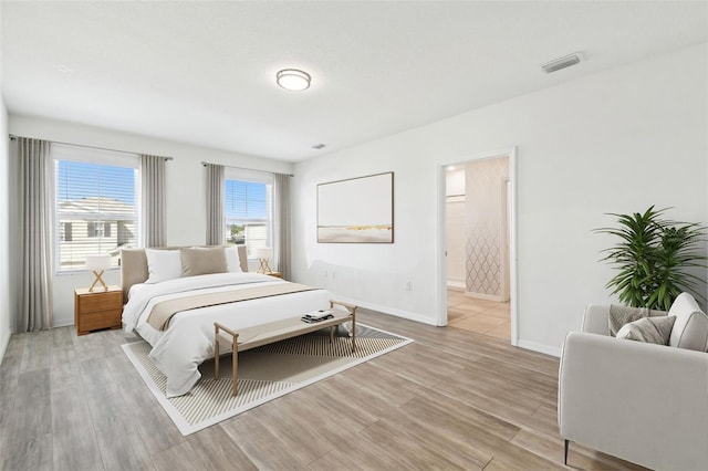 bedroom featuring light wood-type flooring, visible vents, and baseboards