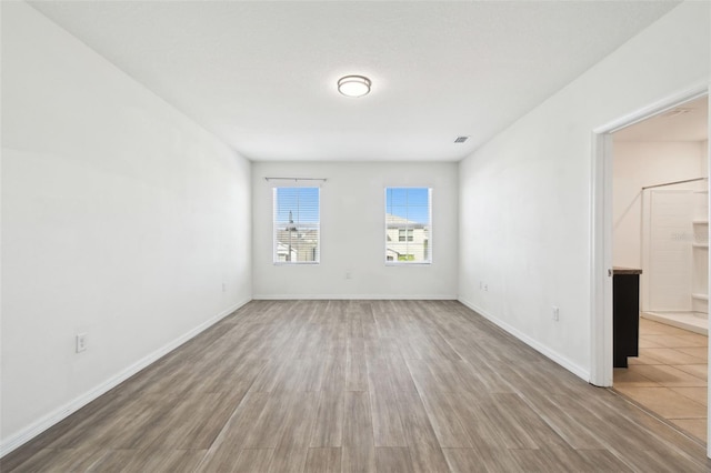 unfurnished room featuring visible vents, baseboards, and wood finished floors