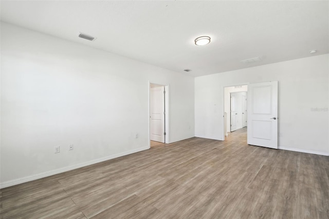 empty room featuring baseboards, visible vents, and wood finished floors