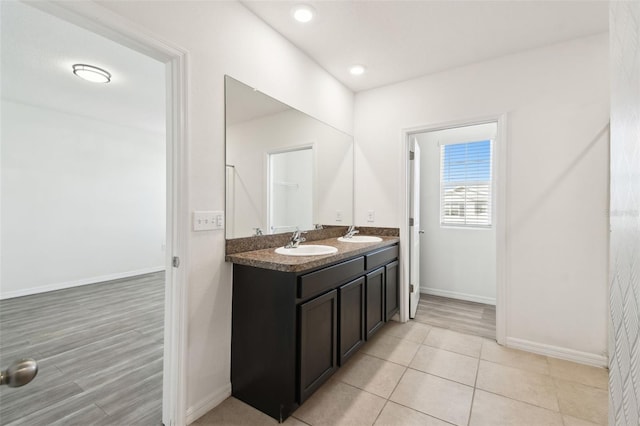 full bathroom with double vanity, baseboards, and a sink