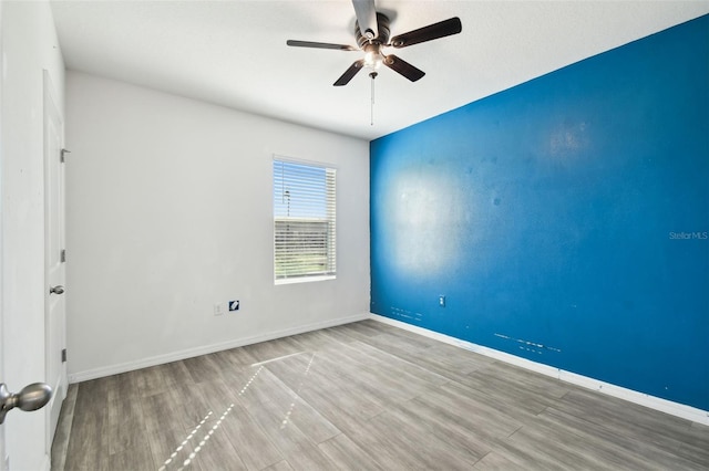 empty room with ceiling fan, wood finished floors, and baseboards