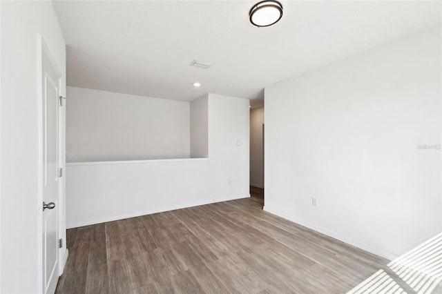 spare room featuring wood finished floors, visible vents, and baseboards