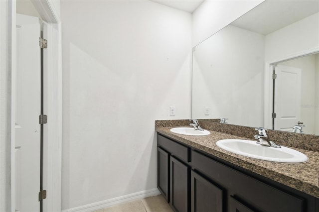 bathroom with tile patterned floors, a sink, baseboards, and double vanity