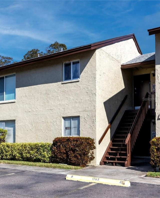 view of building exterior with stairs and uncovered parking