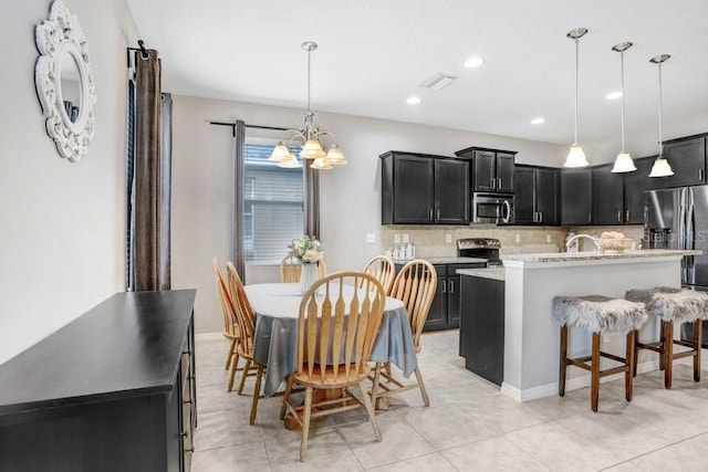 kitchen featuring a kitchen island with sink, dark cabinets, visible vents, appliances with stainless steel finishes, and pendant lighting