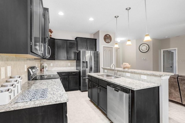 kitchen featuring appliances with stainless steel finishes, decorative light fixtures, an island with sink, and dark cabinetry