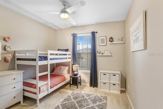 bedroom featuring light carpet, a ceiling fan, and baseboards