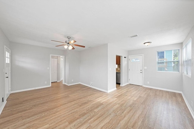 unfurnished living room featuring light wood-type flooring, visible vents, ceiling fan, and baseboards