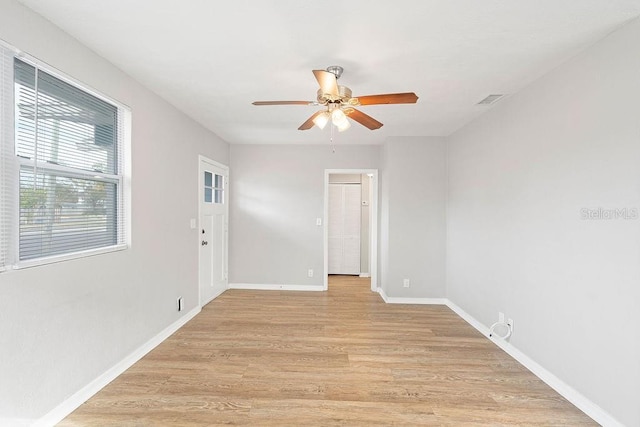 spare room featuring ceiling fan, visible vents, light wood-style flooring, and baseboards