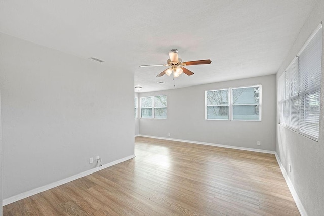 unfurnished room with light wood-style flooring, visible vents, and baseboards