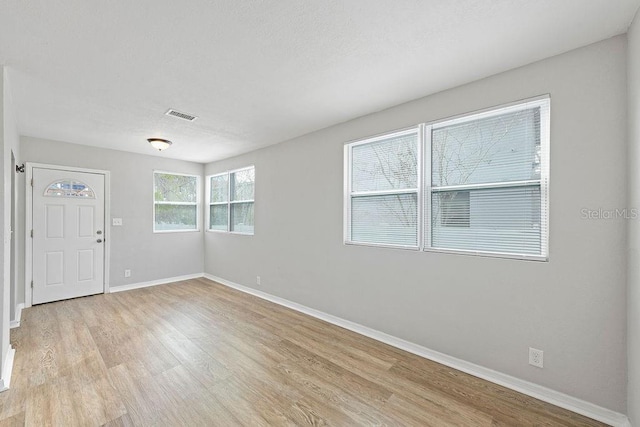 unfurnished room with light wood finished floors, baseboards, and visible vents