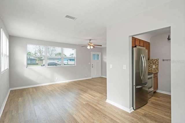 empty room featuring ceiling fan, light wood-type flooring, visible vents, and baseboards