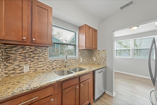 kitchen featuring visible vents, dishwasher, a sink, light stone countertops, and backsplash