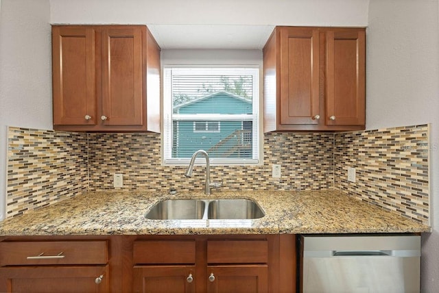 kitchen featuring light stone counters, backsplash, brown cabinetry, a sink, and dishwasher