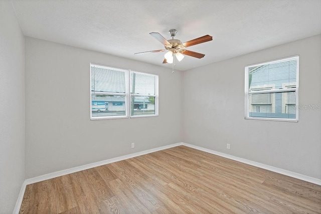 unfurnished room with light wood-style floors, a wealth of natural light, and baseboards