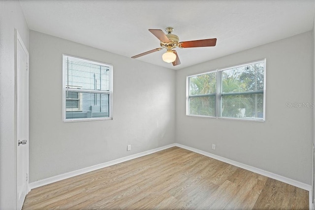 spare room featuring a ceiling fan, light wood-type flooring, plenty of natural light, and baseboards