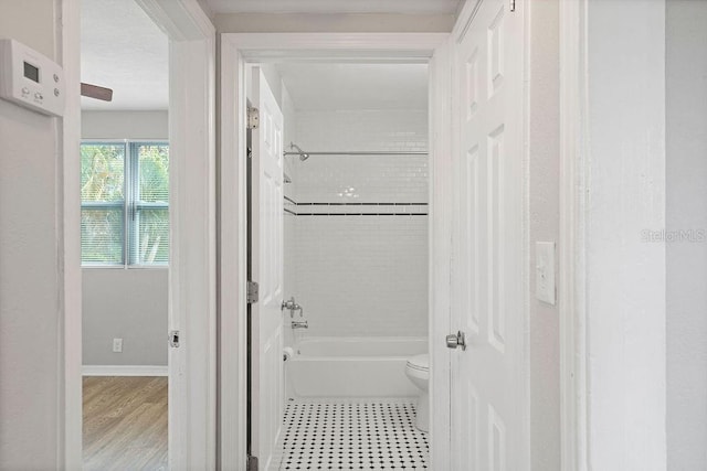 full bathroom with shower / bathing tub combination, toilet, and baseboards