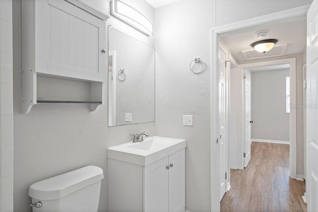 bathroom featuring toilet, baseboards, wood finished floors, and vanity