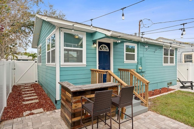 view of front of property featuring a gate, fence, and a patio