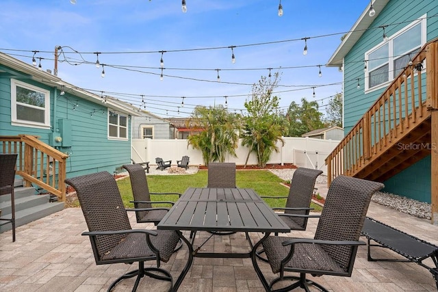 view of patio featuring outdoor dining space, a fenced backyard, and stairs