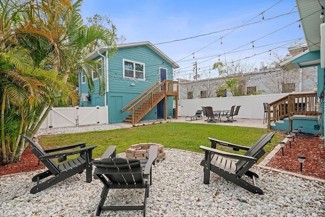 rear view of property featuring a patio, stairway, a gate, a fenced backyard, and a fire pit