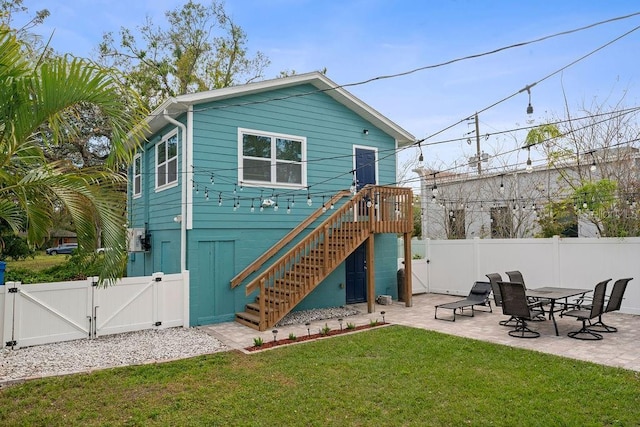 back of property featuring a yard, a gate, a patio area, fence, and stairs