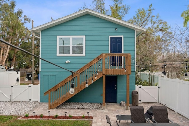 rear view of property featuring stairs, a patio, fence, and a gate