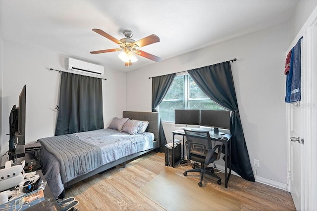 bedroom featuring light wood-type flooring, baseboards, a ceiling fan, and a wall mounted air conditioner