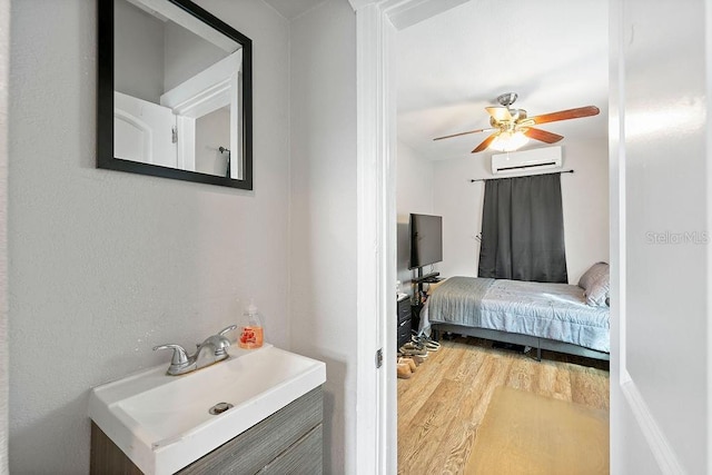 bedroom featuring ceiling fan, wood finished floors, a sink, and a wall mounted AC