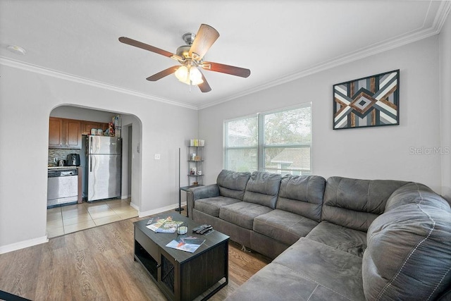 living area featuring light wood-type flooring, baseboards, arched walkways, and ornamental molding