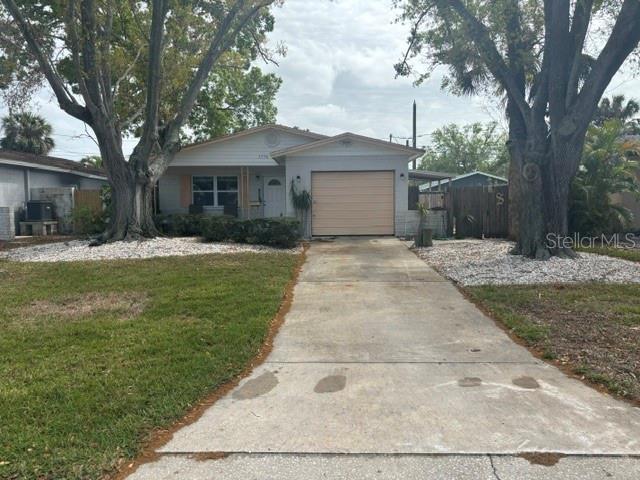 single story home featuring a front lawn, fence, concrete driveway, central AC unit, and an attached garage