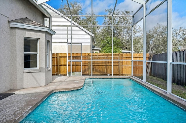 view of swimming pool featuring glass enclosure, a patio, a fenced backyard, and a fenced in pool