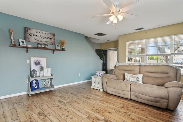 living area with light wood-style flooring, visible vents, ceiling fan, and baseboards