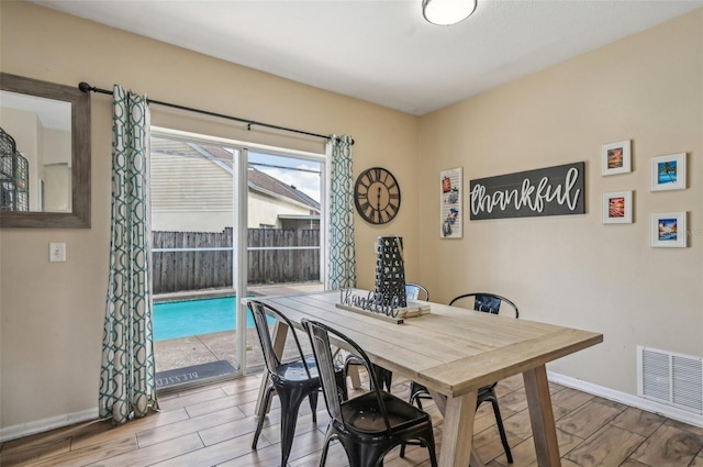 dining area with baseboards, visible vents, and wood tiled floor