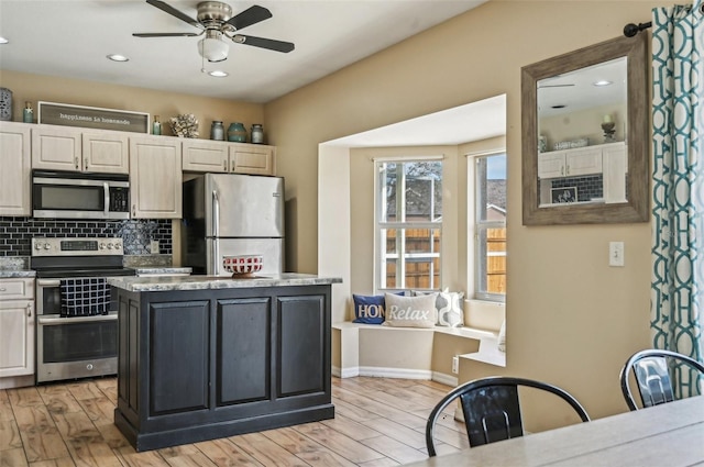 kitchen featuring ceiling fan, light wood-style flooring, a center island, stainless steel appliances, and backsplash