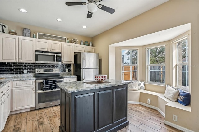 kitchen featuring tasteful backsplash, a kitchen island, appliances with stainless steel finishes, and light wood-style flooring