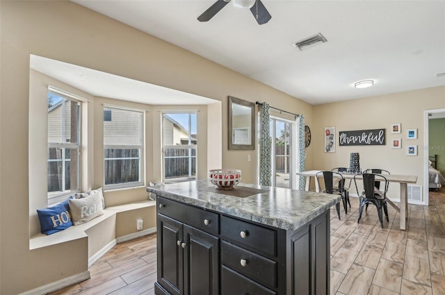 kitchen featuring a kitchen island, visible vents, dark cabinetry, and wood finish floors